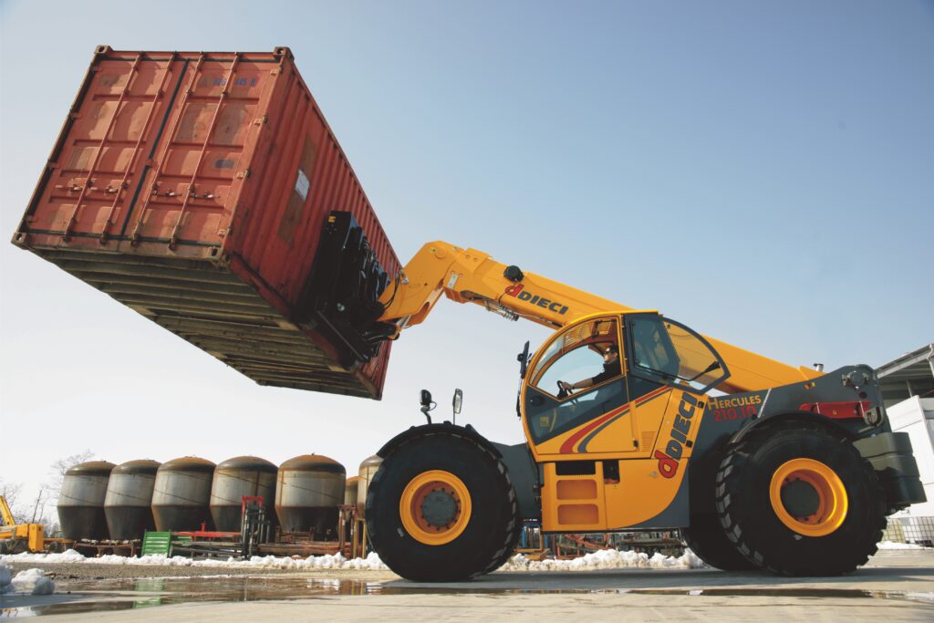 Telehandler lifting a shipping container at a UK industrial site, demonstrating specialist container handling and lifting equipment.